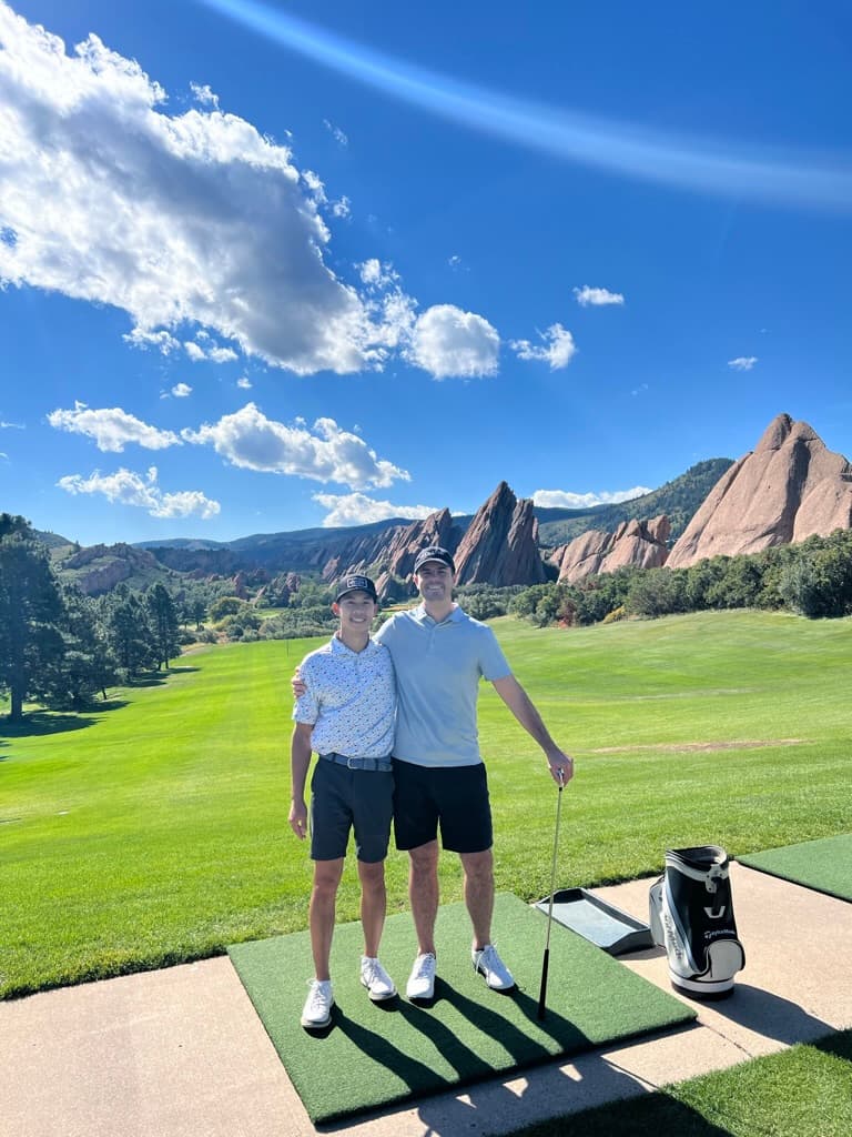 Austin and Curtis on a Colorado golf course with red sandstone rocks behind them.
