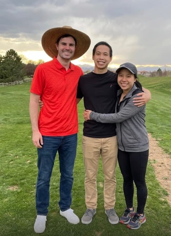 Austin, Curtis, and Megan standing arm-in-arm on a Colorado golf course at dusk.