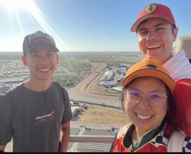 Curtis, Austin, and Megan on a viewing platform overlooking a Formula 1 racetrack on a sunny day.